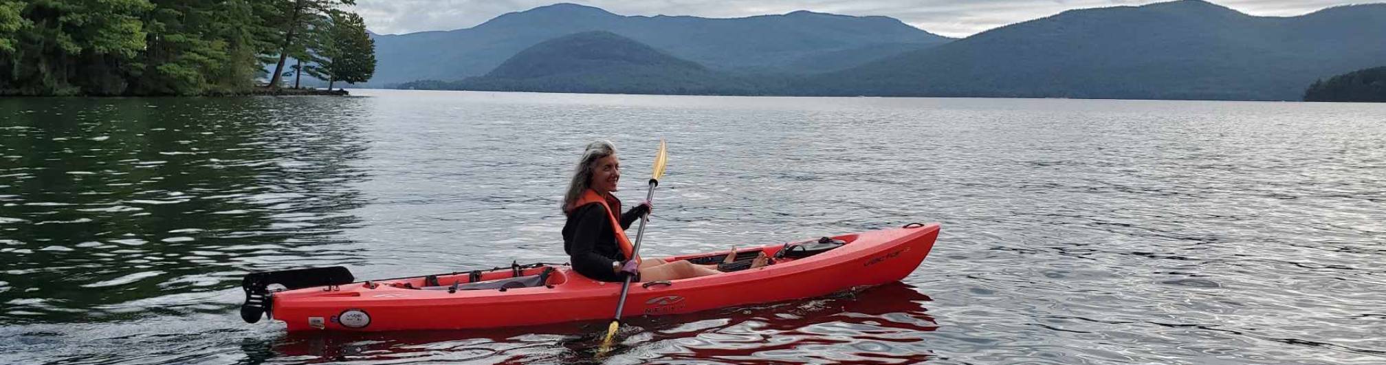 A woman on a kayak at the point cabins, bolton landing.